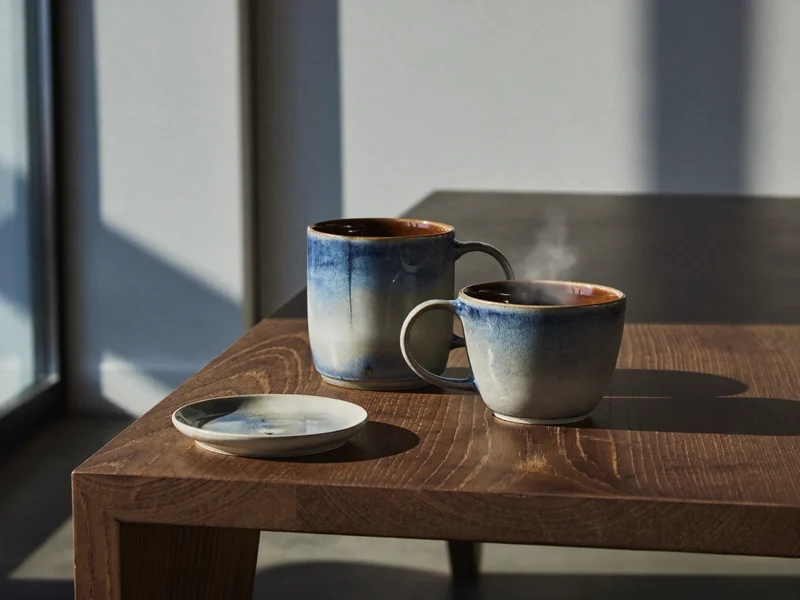Set di ceramica smaltata a mano con tazza e piattino su tavolo scuro